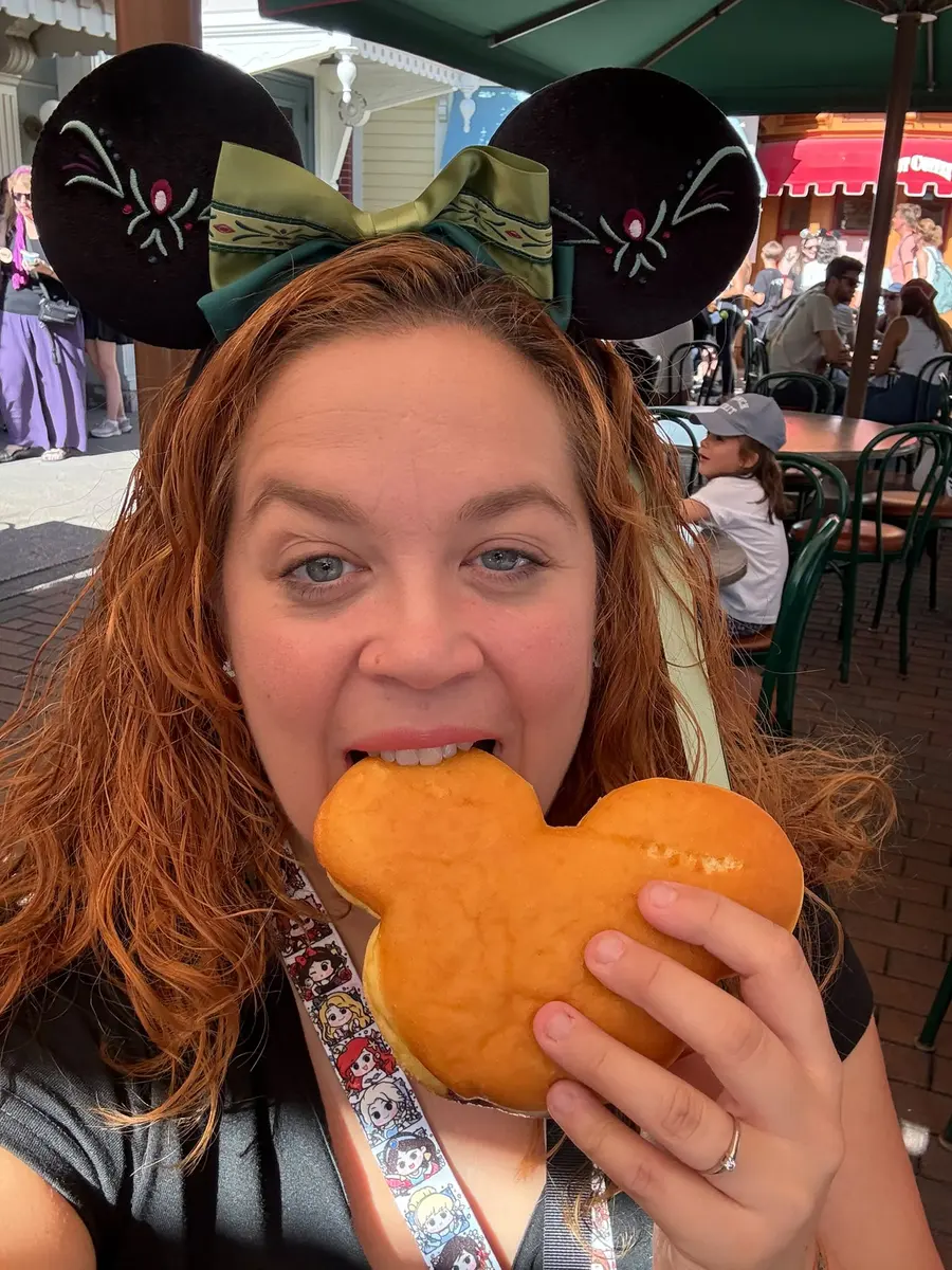 Lara comiendo un buñuelo con forma de Mickey en Disneyland Paris