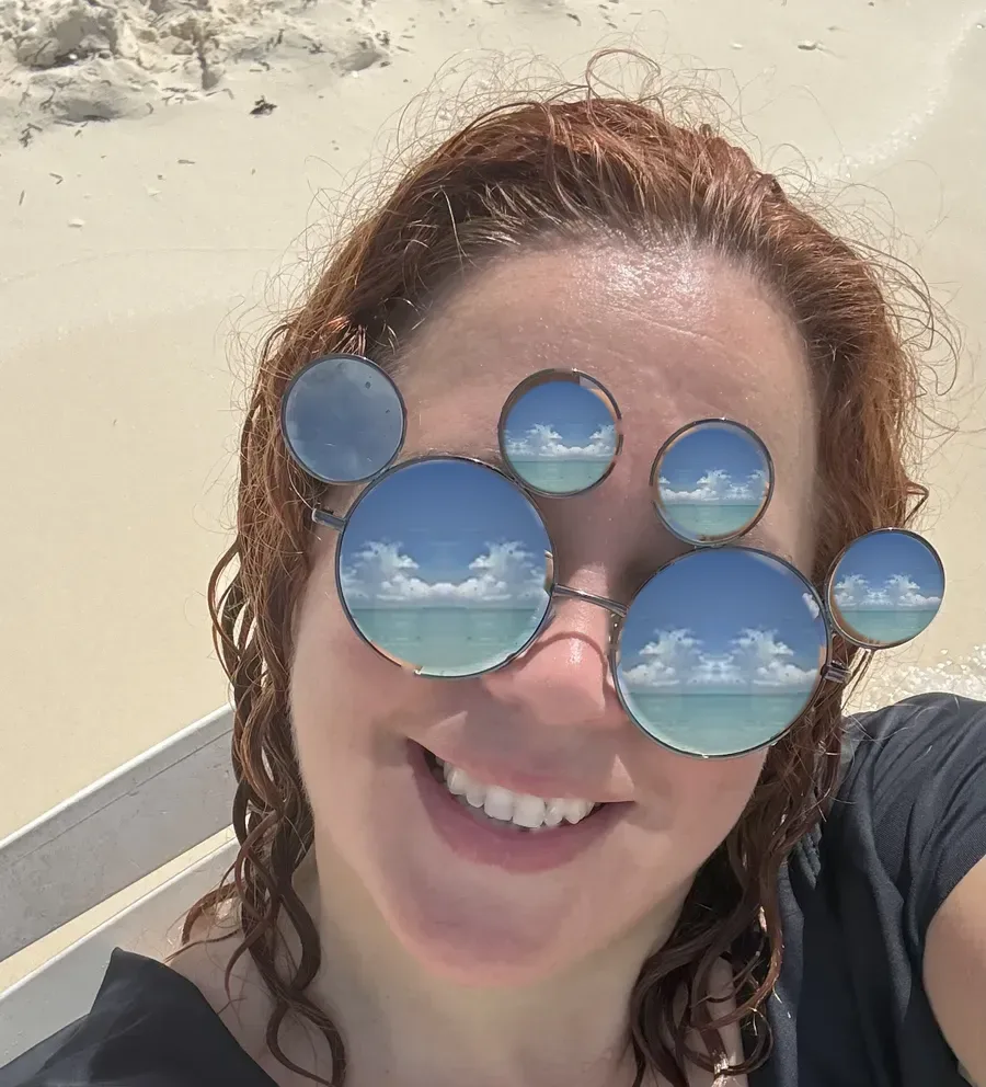Lara con gafas de Mickey que reflejan la playa de Castaway Cay, la isla privada de Disney