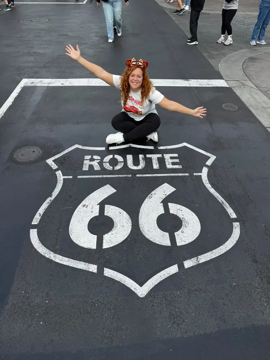 Lara sobre la señal de la Ruta 66 en Cars Land