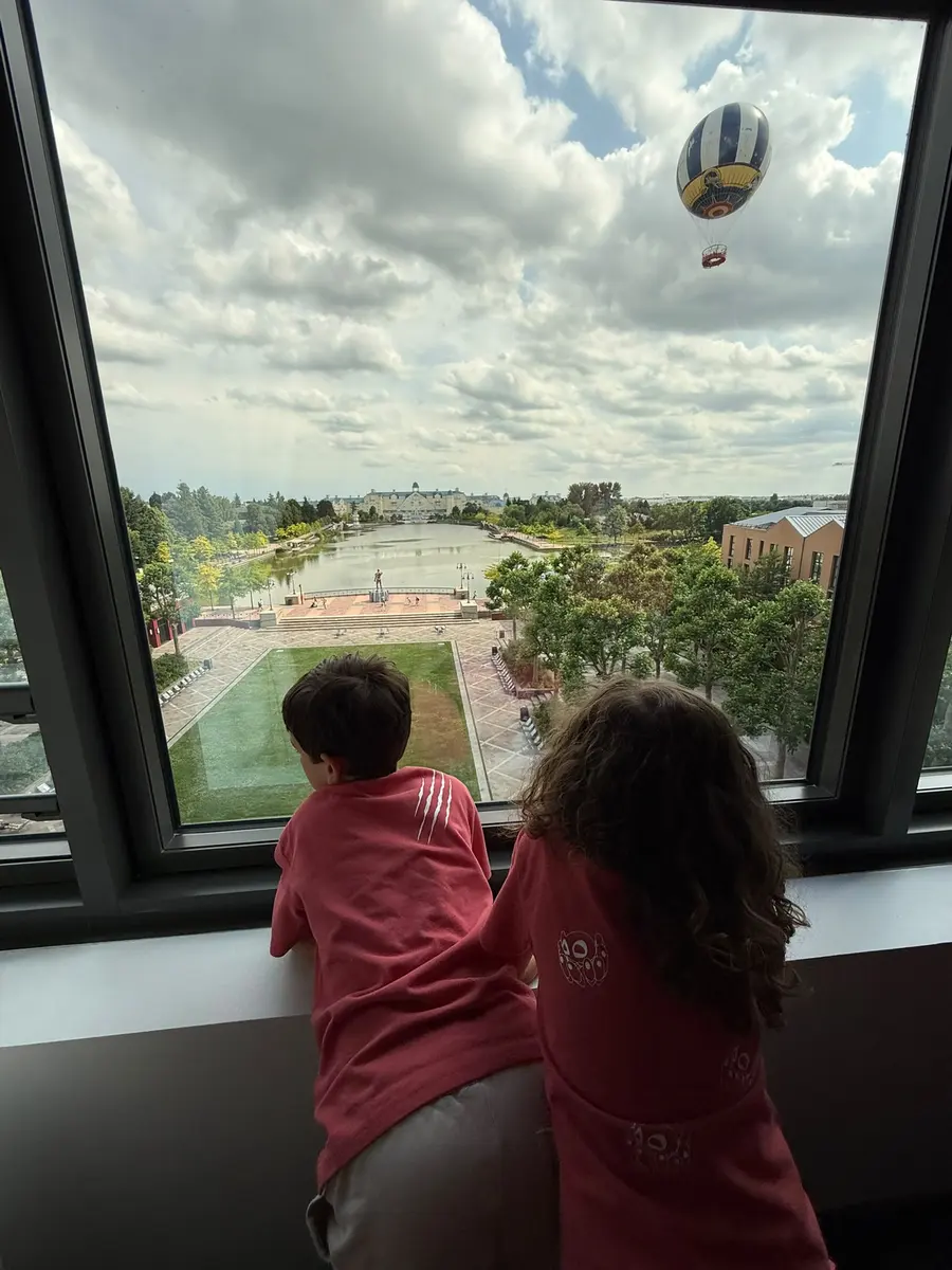 Niños mirando por la ventana del Disneyland Hotel las vistas a Disneyland Paris